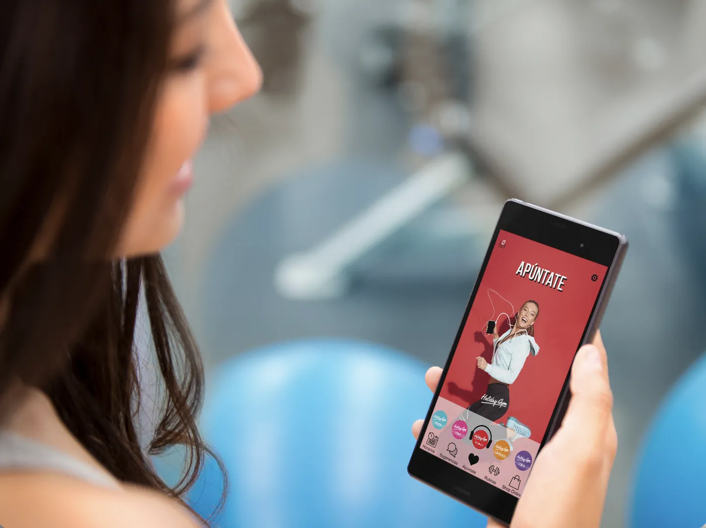 Socia de Holiday Gym consultando en el gimnasio la app creada con Scoreapps, con reservas, horarios, rutinas y tienda.